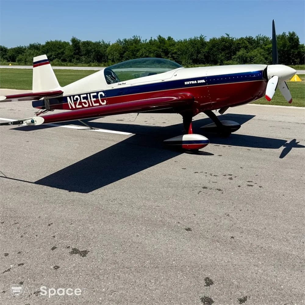 A red, white, and blue Extra 300L aircraft, N251EC, parked on an asphalt runway on a sunny day.