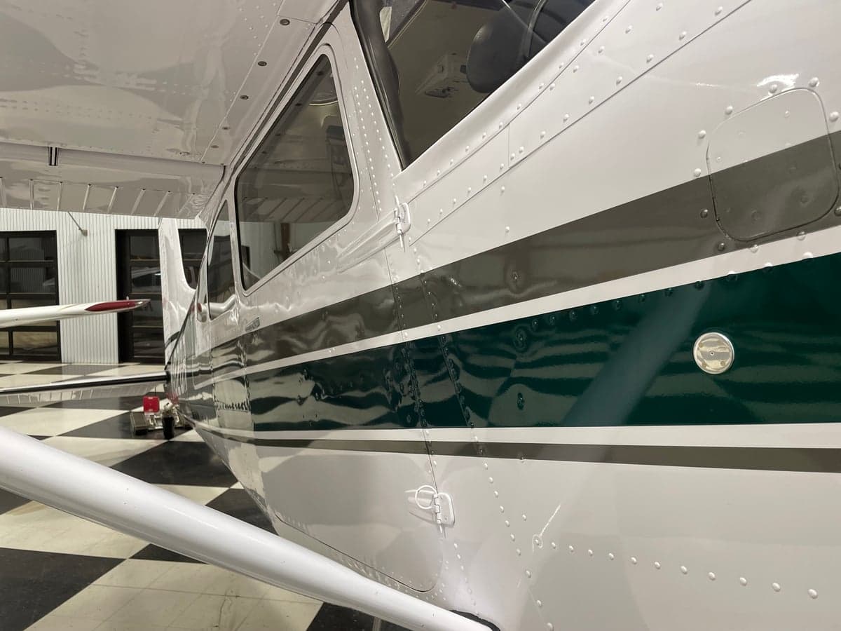 Close-up of the side of the Cessna 185 Skywagon showing the green and white paint scheme.