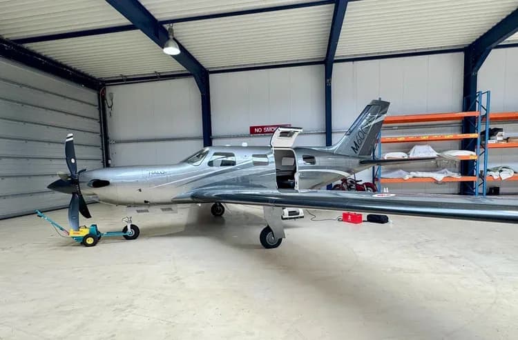 A Piper M600 HALO aircraft parked inside a hangar with the door open.
