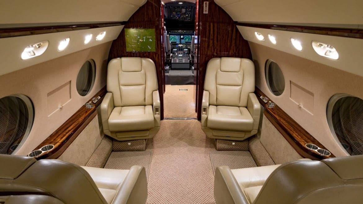 The interior of the aircraft features leather seats and a view of the cockpit.