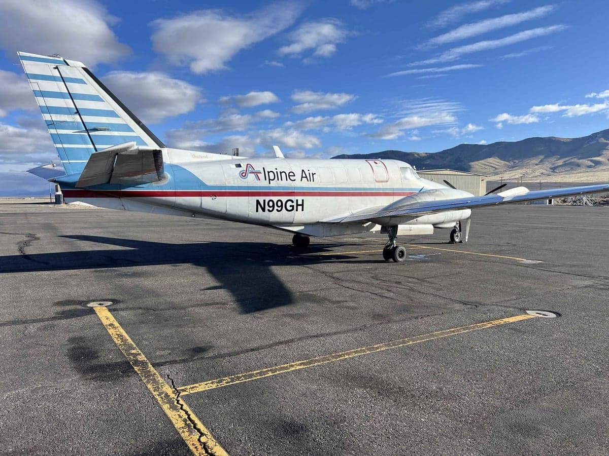 A Beechcraft King Air with a white and blue paint scheme is parked on a cracked tarmac.