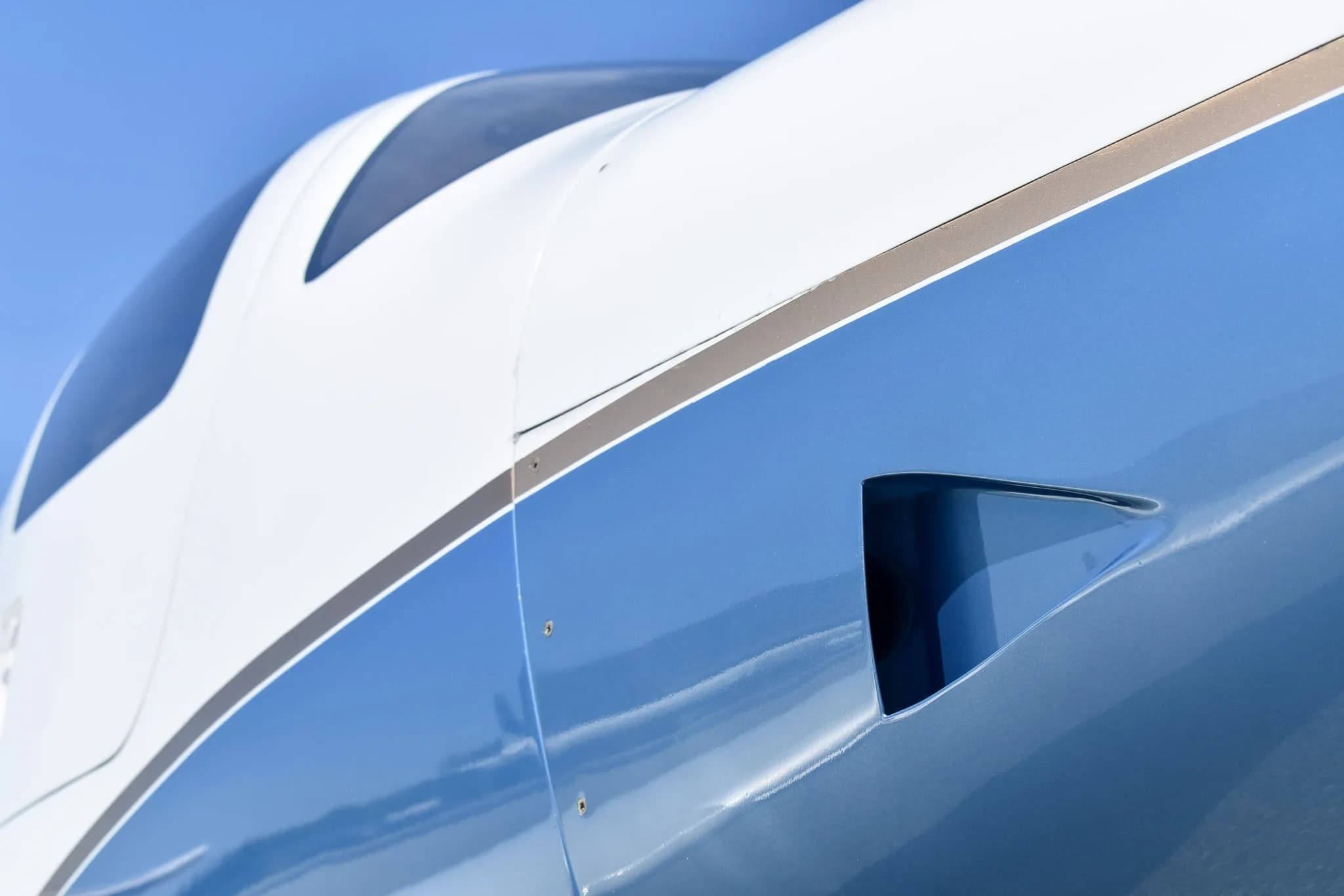 Close-up view of the white and blue fuselage of the aircraft, showing an air intake.