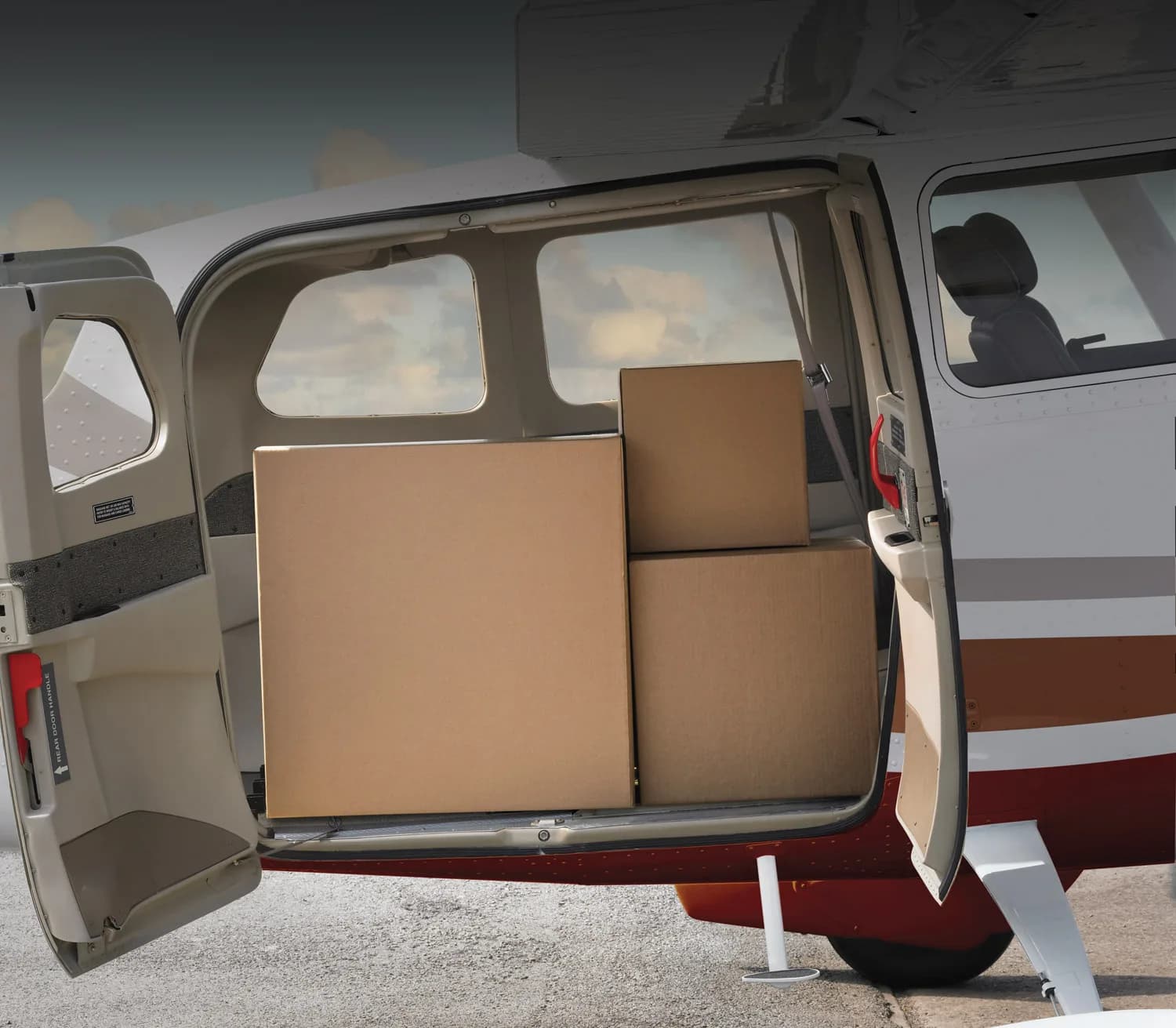 The open cargo door of a Cessna Stationair with boxes inside.