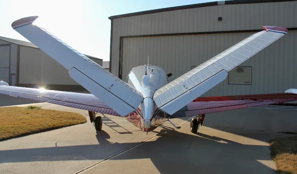 A rear view of a red and white Beechcraft Bonanza N5724V, highlighting its distinctive V-tail.