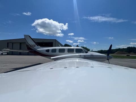 A white and maroon twin-engine aircraft, N30DF, parked on the tarmac, seen from the wing of another aircraft.
