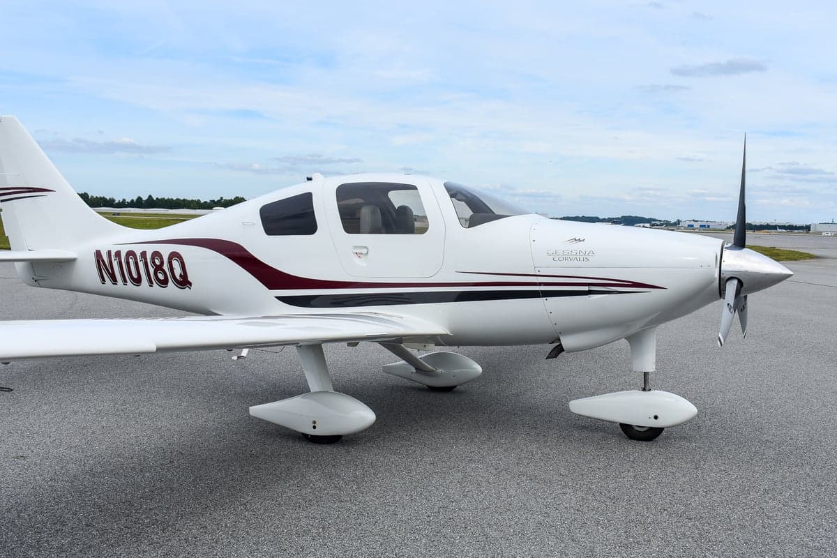 Front view of a white Cessna Corvalis with open doors on the tarmac.