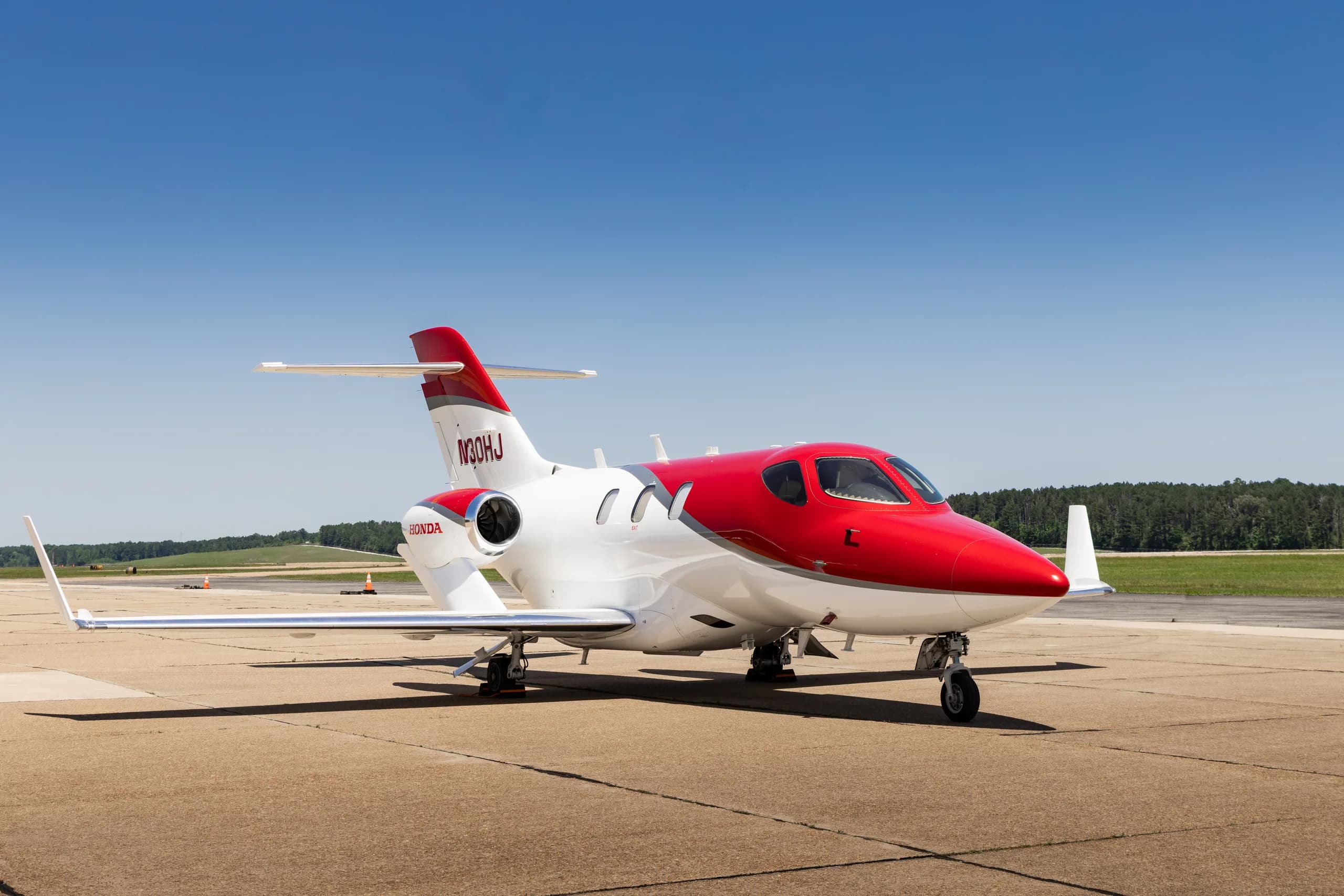 A white and red HondaJet HA-420 (N30HJ) parked on a tarmac, viewed from the front-right.
