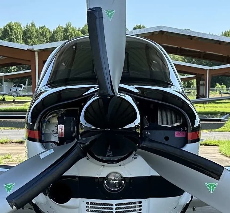 A head-on view of the black and white Beechcraft Bonanza, highlighting its propeller and nose.