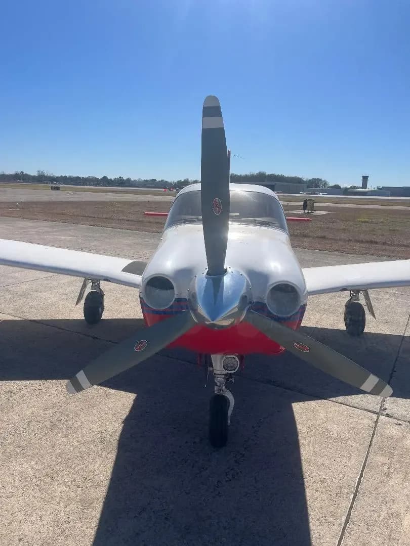 A head-on view of a red and white single-engine propeller aircraft, N3258H, on an airfield.