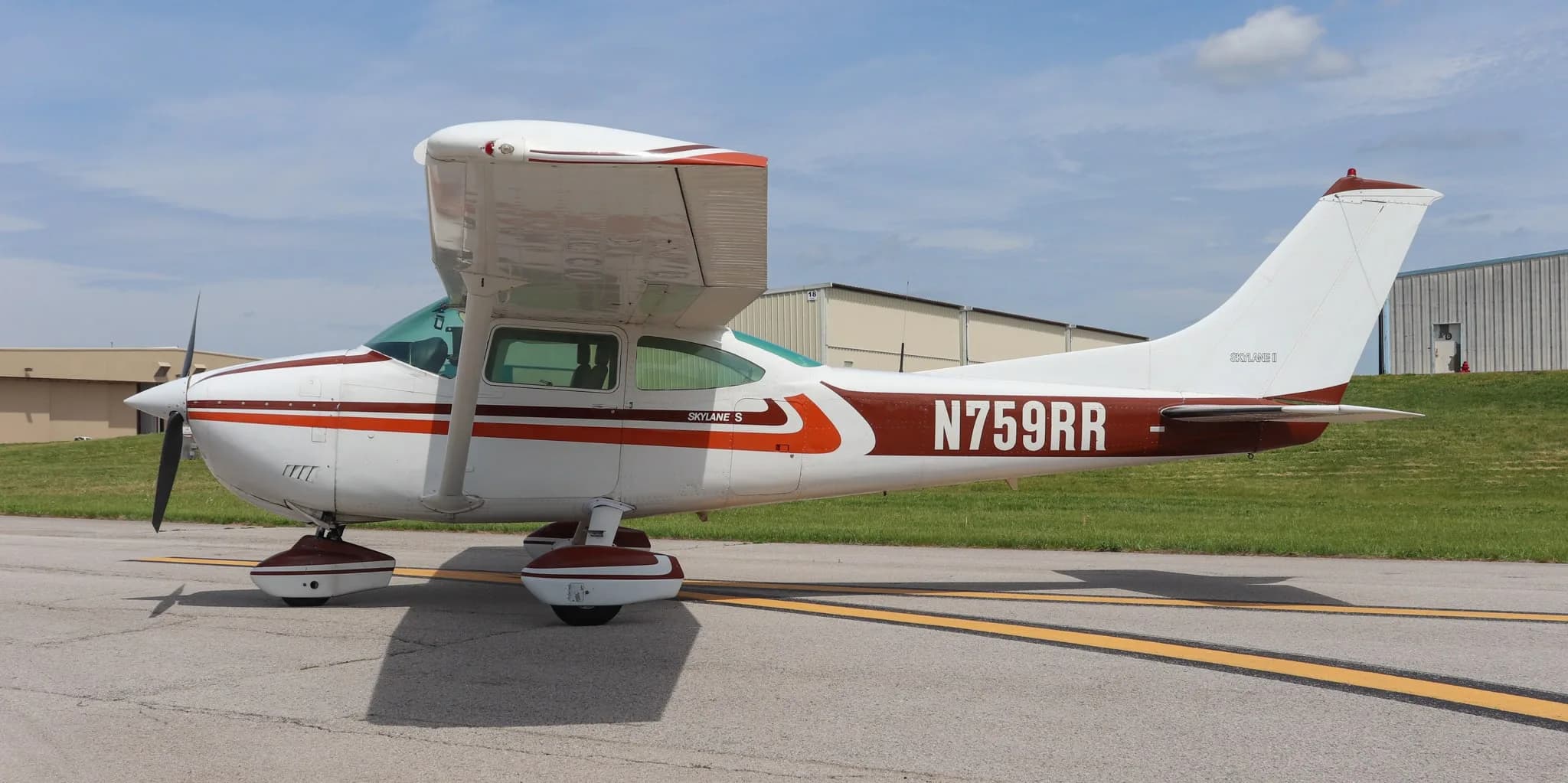 A side view of the Cessna Skylane S (N759RR) with its white and brown paint scheme on an airfield.