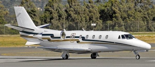 Side view of a white and gold Cessna Citation jet on the tarmac.