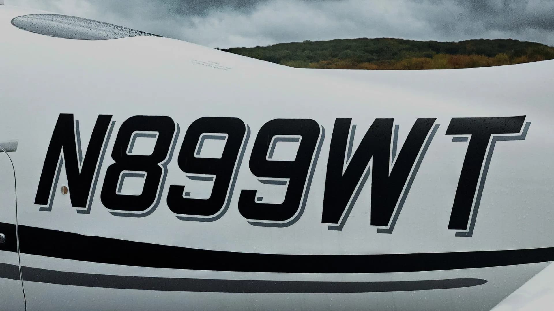 A close-up view of the registration N899WT on the side of a white Cirrus aircraft.
