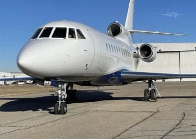 A white and blue Dassault Falcon 900EX, registration C-GEOS, parked on the tarmac.
