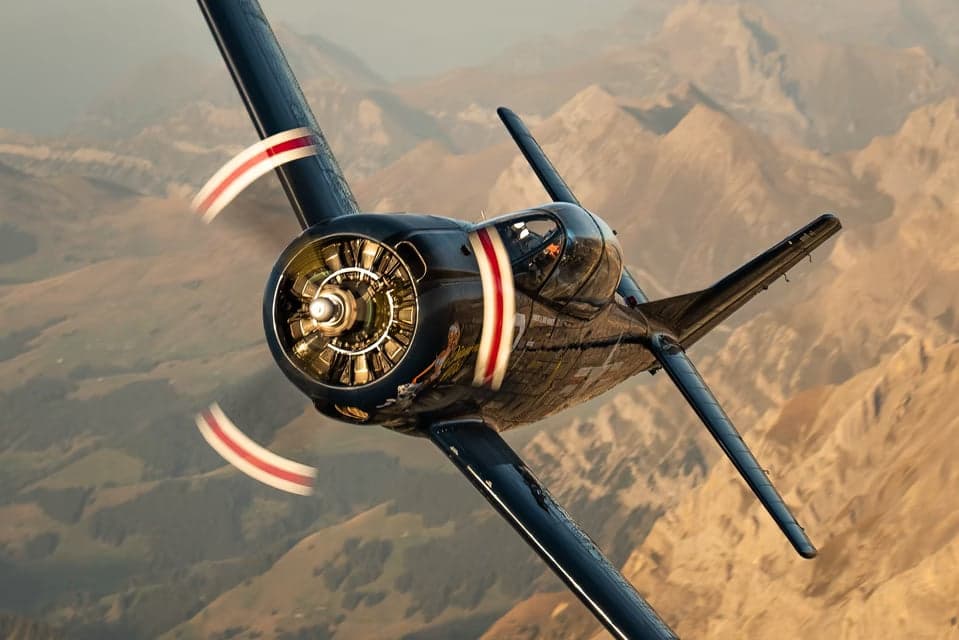 HB-RMW T-28B Trojan flying over a valley.