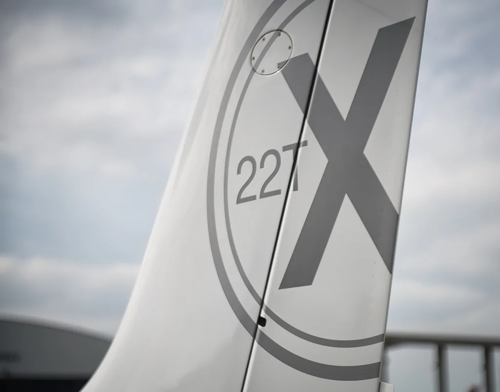 A close-up view of the vertical stabilizer of the Cirrus SR22T, featuring a large 'X' and '22T' logo.