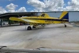 Yellow and blue agricultural aircraft parked on a concrete surface.