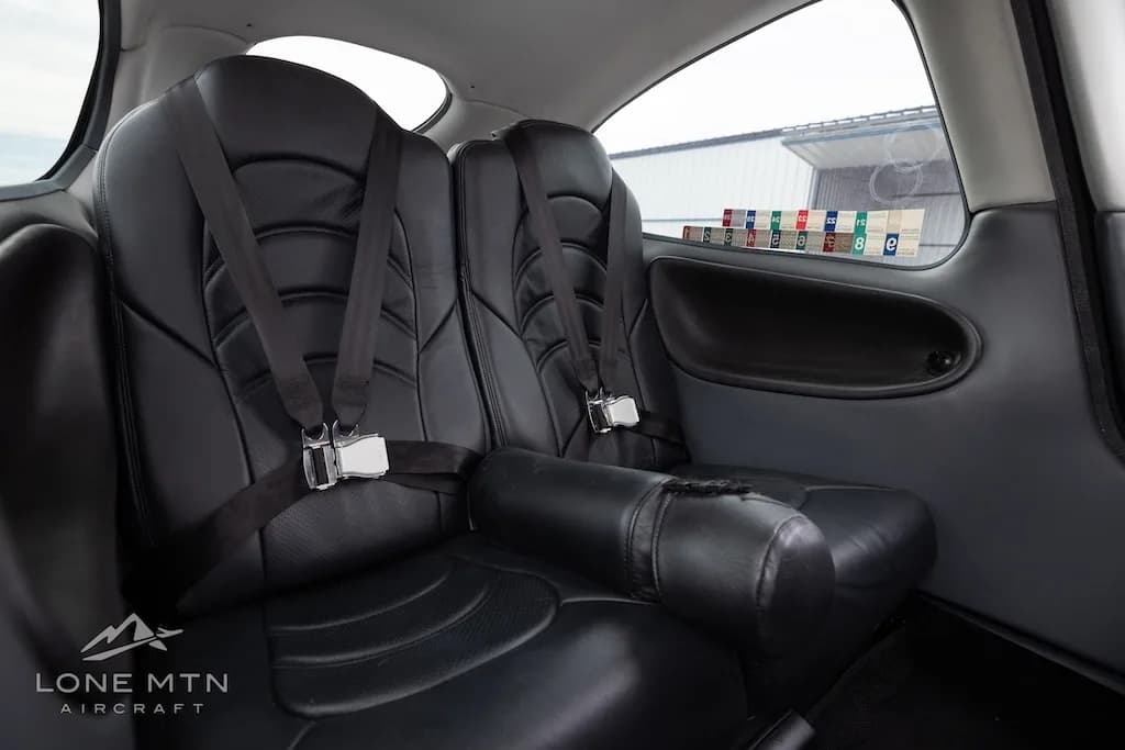 A close-up side view of the black leather rear seats with harnesses in the Cirrus SR22.