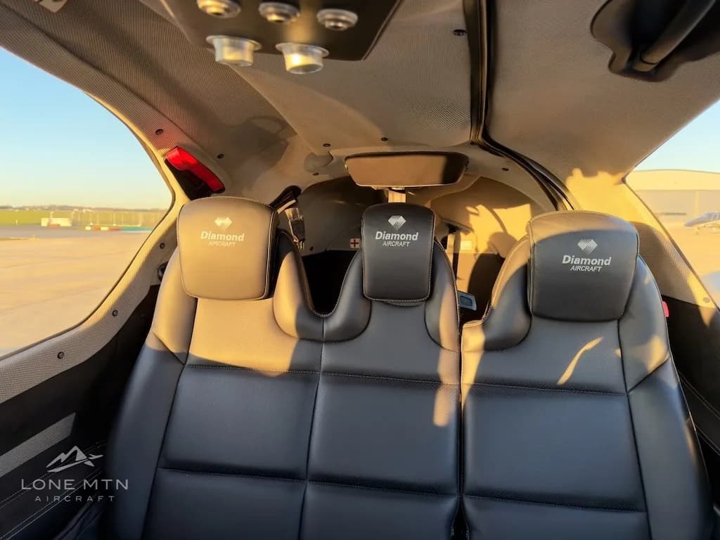 The three black leather rear passenger seats of a Diamond DA50 aircraft, with "Diamond Aircraft" embroidered on the headrests.