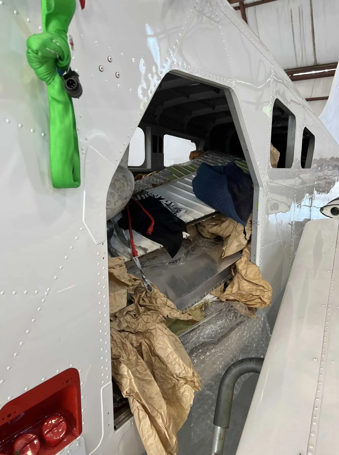 A close-up of the open fuselage of a white aircraft, revealing packing materials and internal structures.