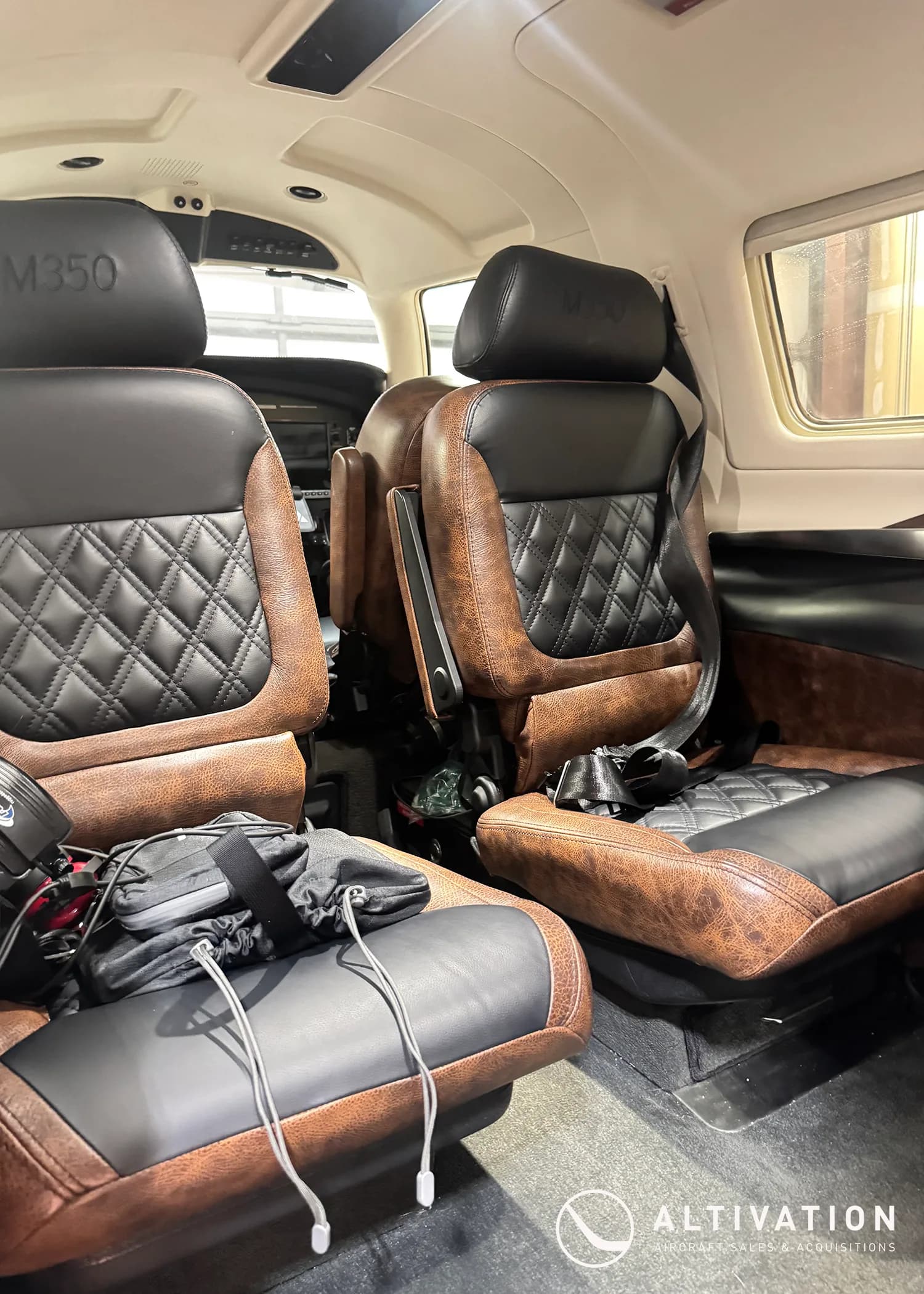 The brown and black quilted leather interior seats of a Piper M350 aircraft cabin.