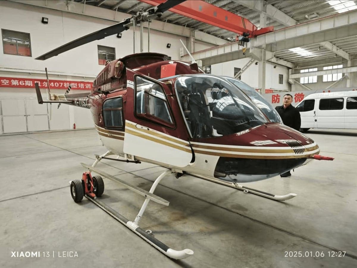 Side view of a red and white helicopter with the door open inside a hangar.
