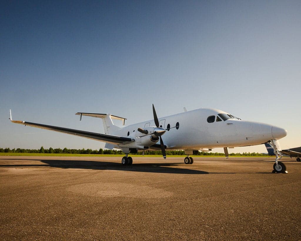 Side view of a white Beechcraft King Air aircraft parked on the tarmac.