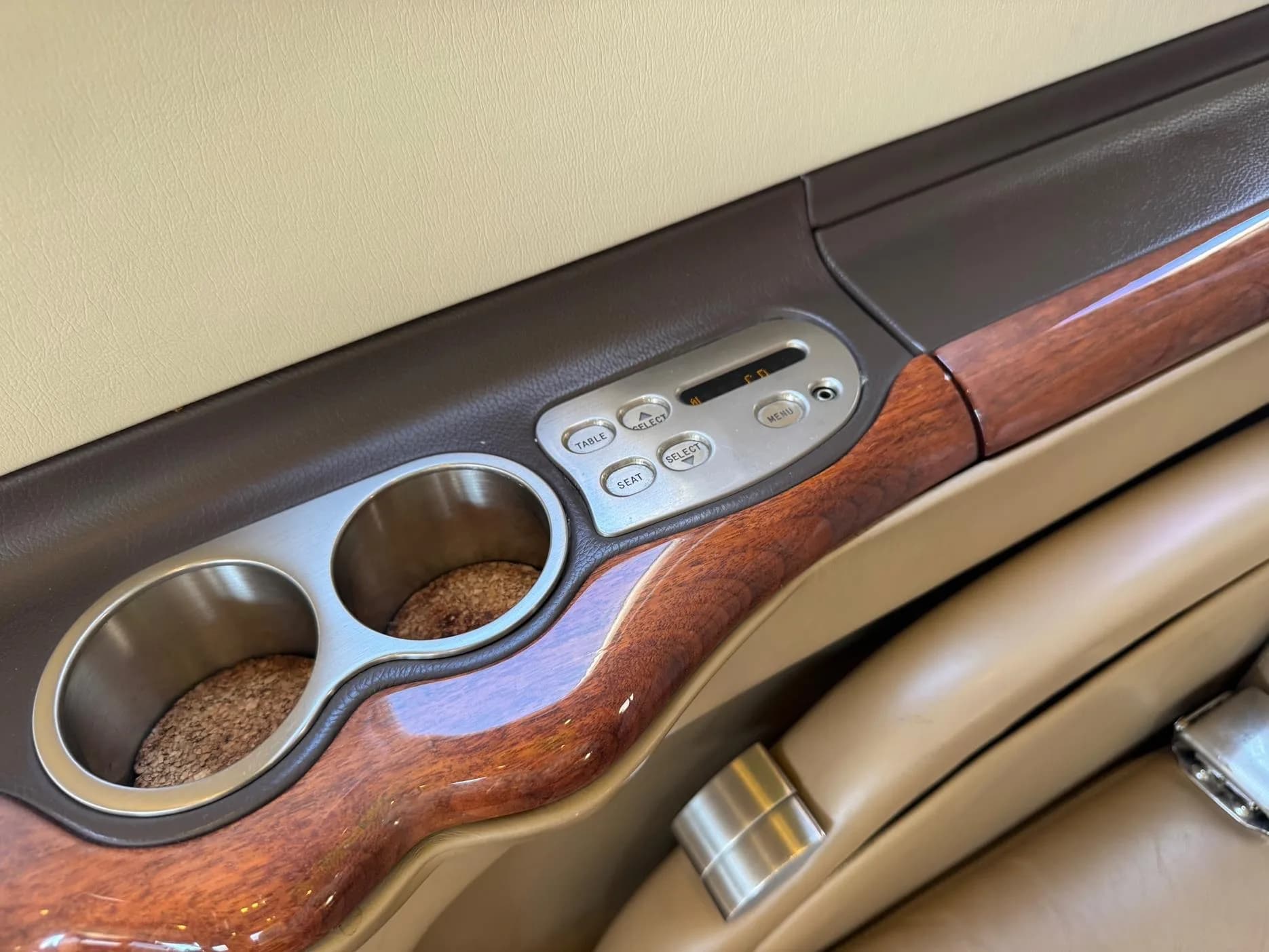 Close up of the aircraft interior with cup holders and seat controls.