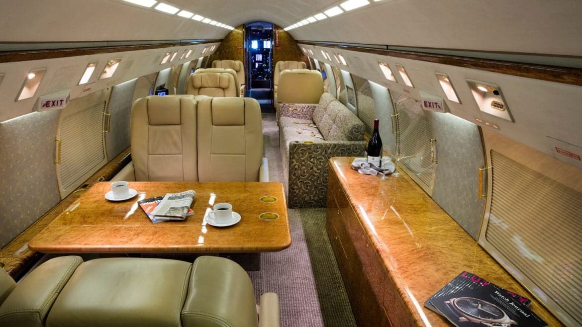 Interior of the aircraft featuring leather seating, wooden tables, and a sofa.