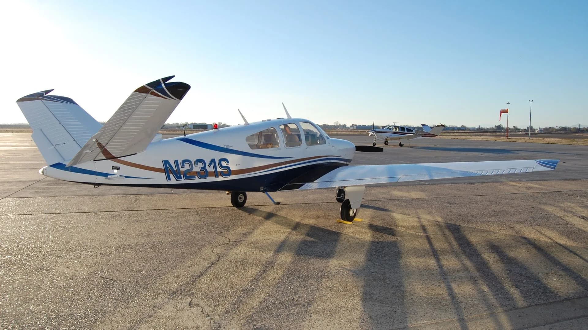 Side view of the N231S aircraft parked on the tarmac with other aircraft in the background.