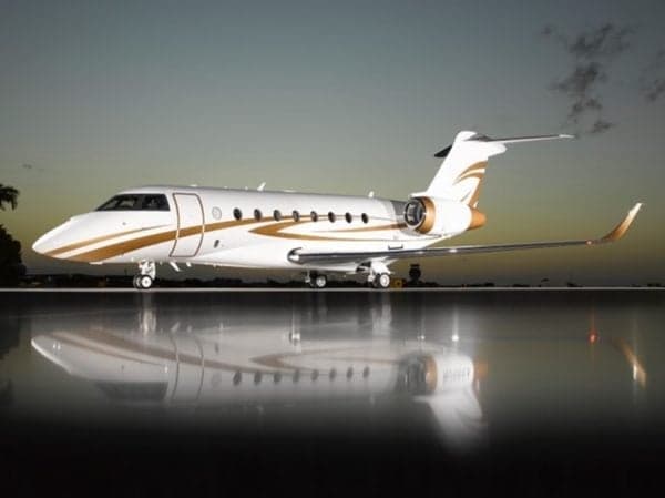 A white and gold aircraft is parked on a reflective surface at dusk.