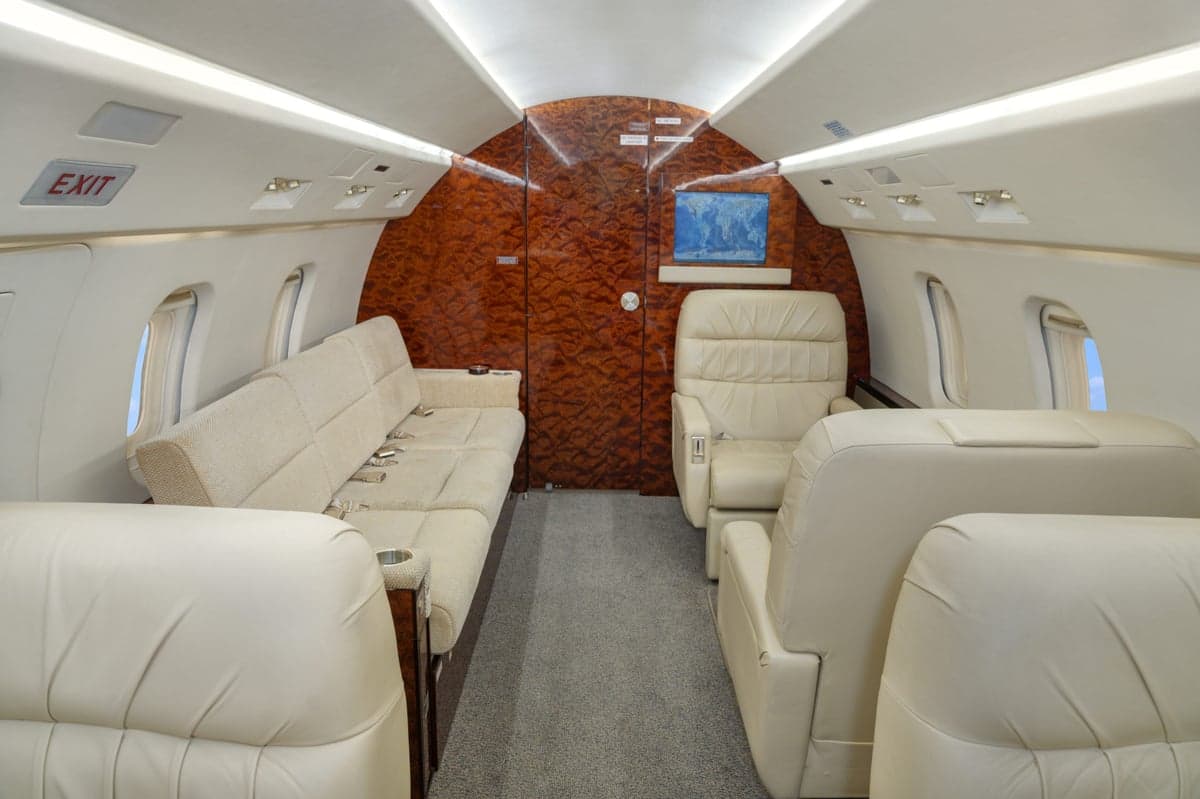 A view of the aircraft cabin with a sofa and cream-colored leather seats.