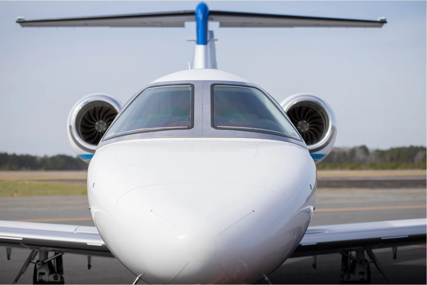 A front view of the white and blue N232JS aircraft on the tarmac.