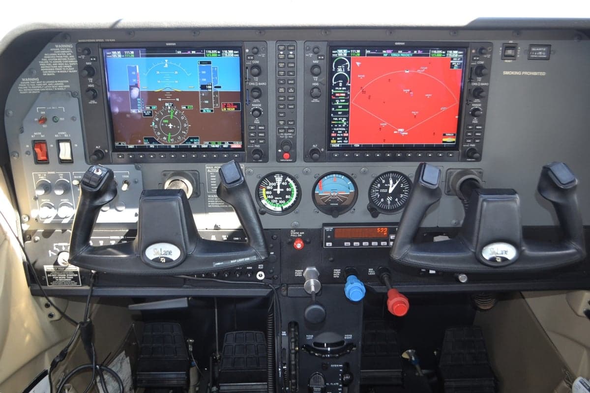 The instrument panel of the aircraft with dual screens and flight controls.
