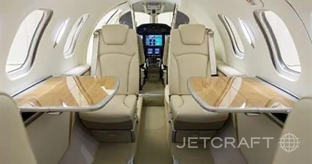 The interior cabin of a HondaJet features beige leather seats, fold-out tables, and a view towards the cockpit.