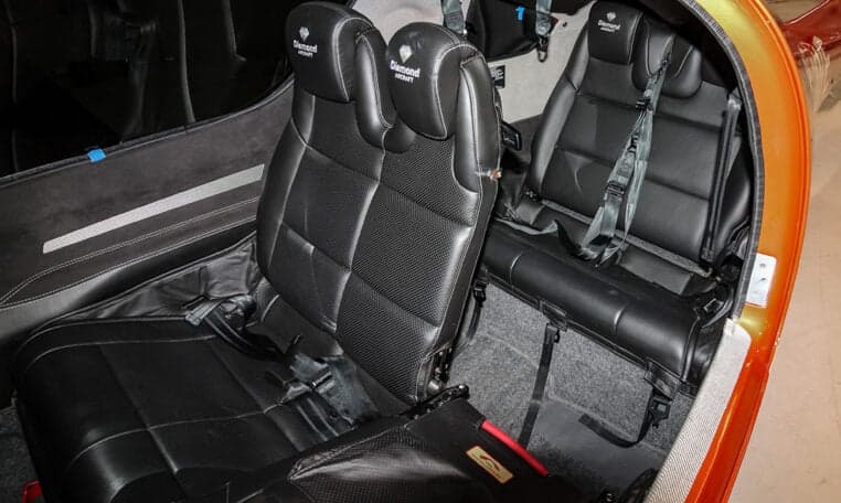 The interior of a Diamond DA62 aircraft features black leather seats and a spacious cabin.