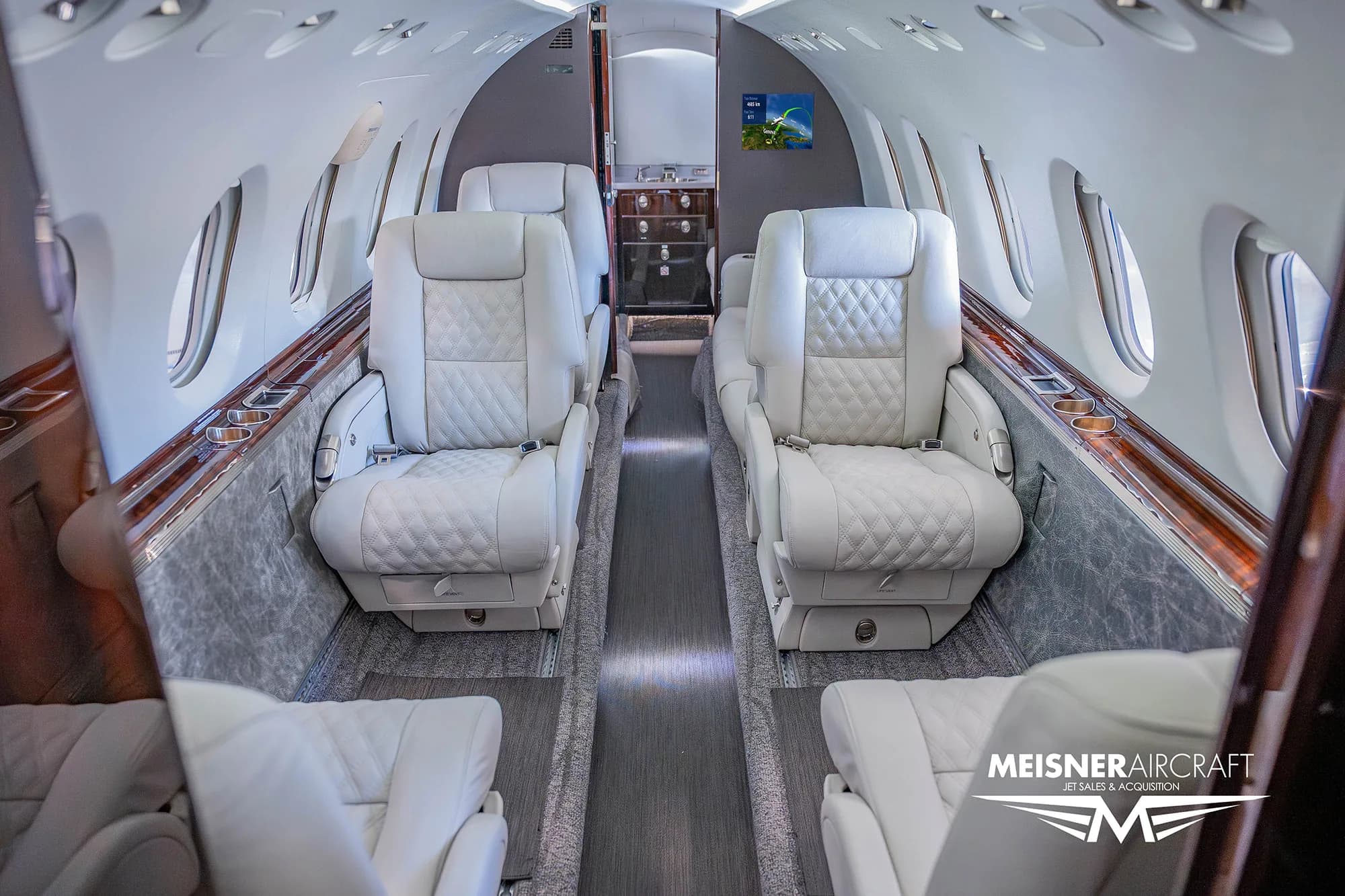 The luxurious white leather interior cabin of a business jet with quilted seats.