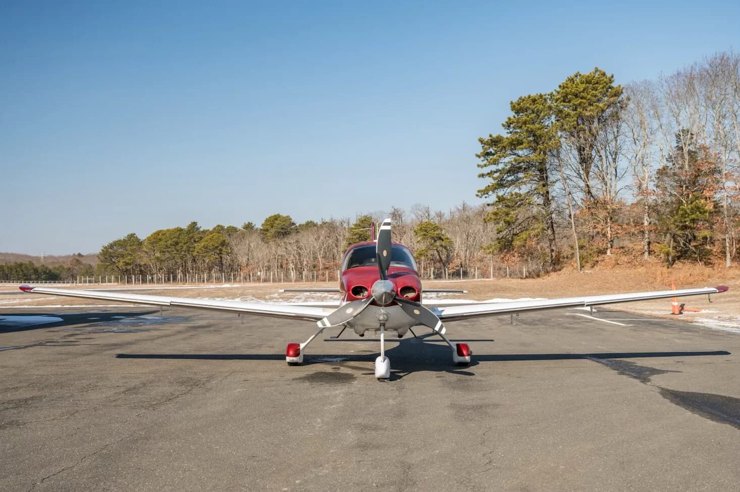 A head-on view of a red and white Cirrus SR22T aircraft, N799SR, parked on an tarmac.