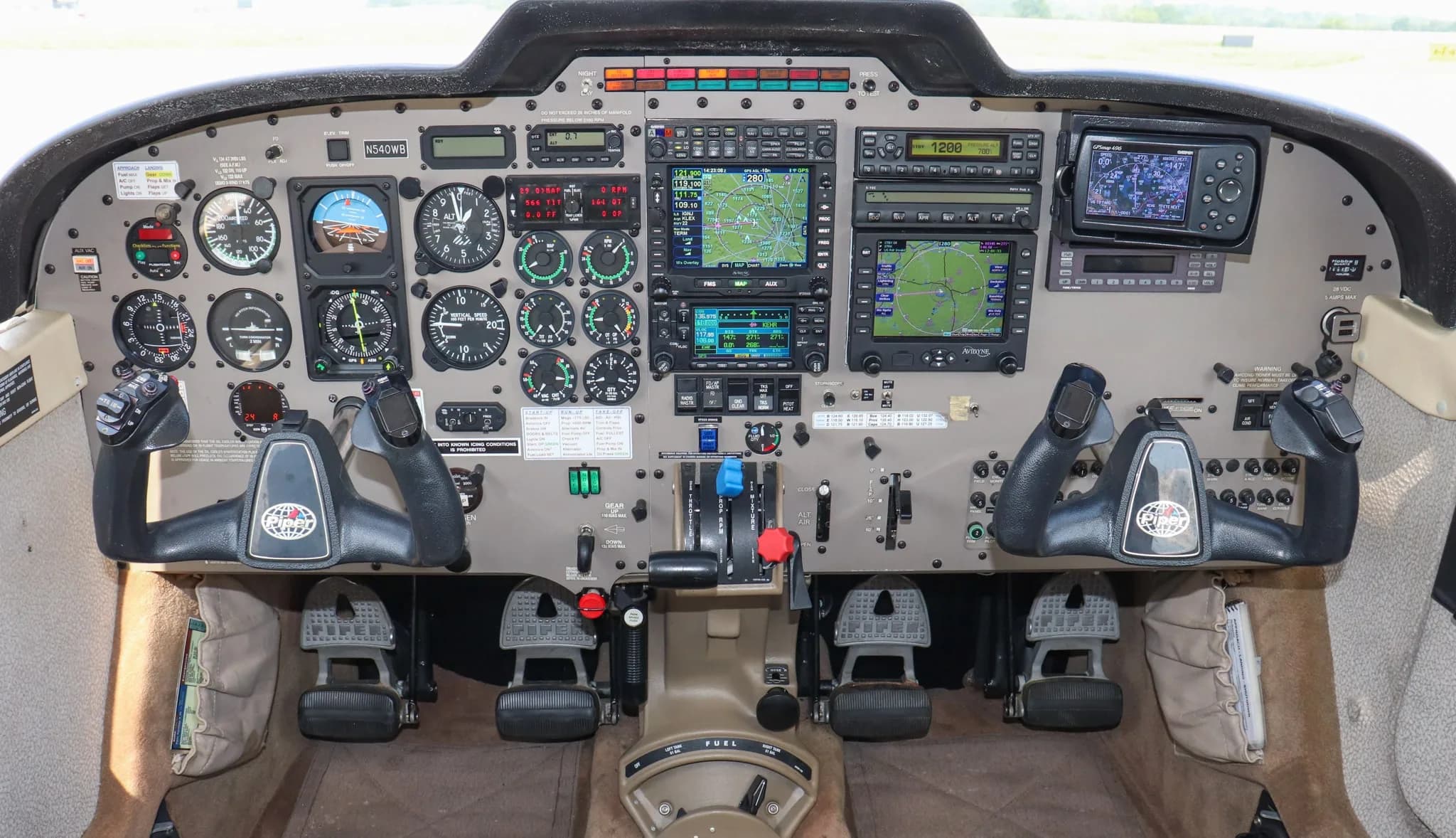 A detailed view of the cockpit of a Piper Saratoga II TC, showing the instrument panel, yokes, and avionics.