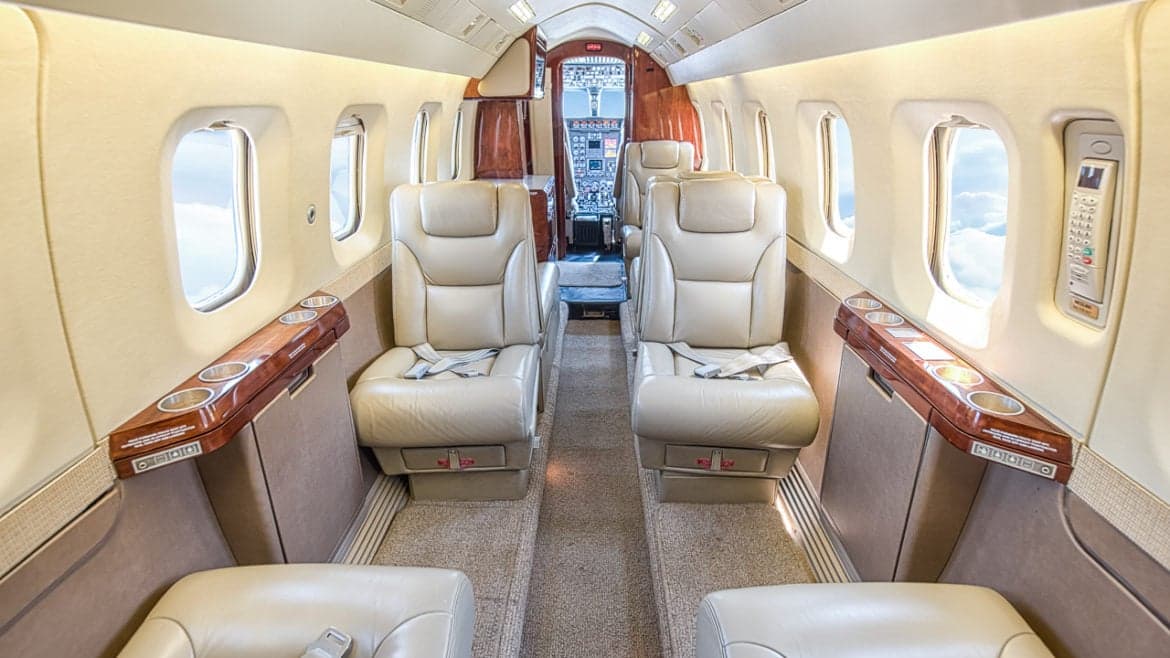 View of the aircraft cabin with leather seats and wood trim.