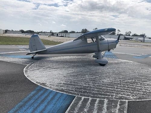 Side view of a silver and blue aircraft on a tarmac.