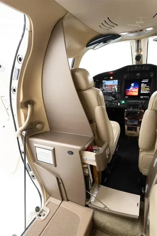 The entry area of the Cessna Citation M2 cabin, showing a storage cabinet with an open drawer and a view towards the cockpit.