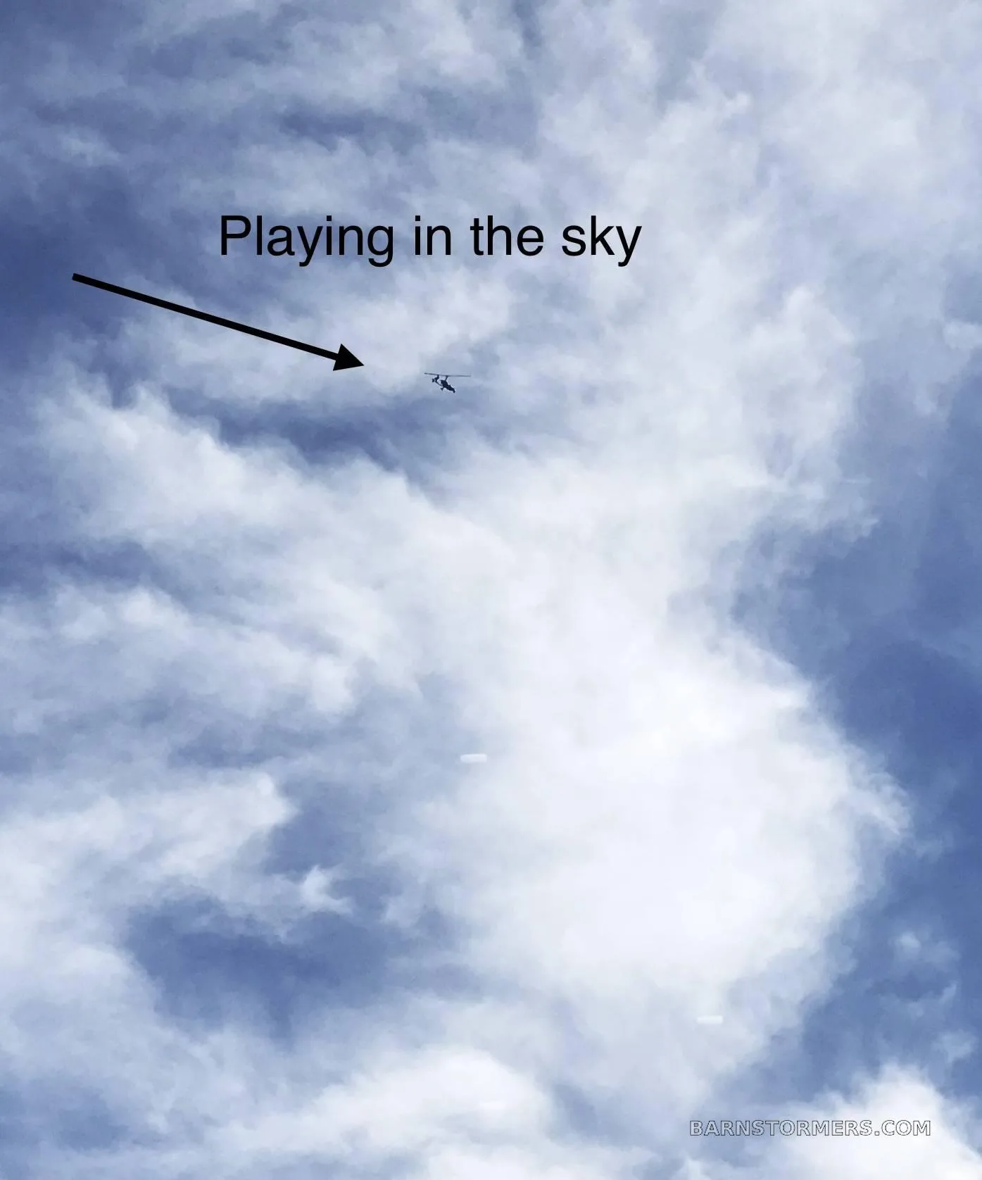 A tiny gyrocopter is seen flying high in a cloudy blue sky, with text 'Playing in the sky' and an arrow pointing to it.