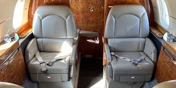 The cockpit of a business jet featuring multiple digital displays and control yokes.