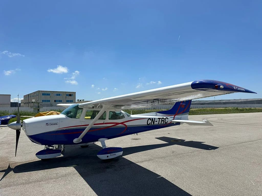 A blue and white Cessna 172 Skyhawk aircraft with registration CN-TRC parked on an airfield under a clear sky.