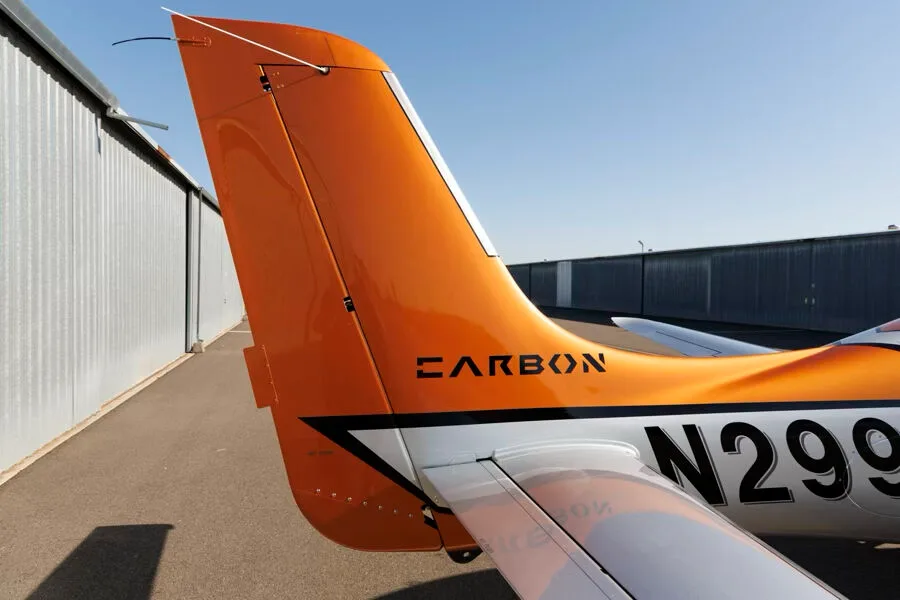 Close-up of the orange tail of a Cirrus SR22T GTS aircraft, showing "CARBON" and part of registration N299WT.