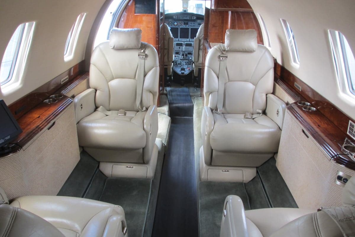 Aircraft cabin with leather seats and wood trim.
