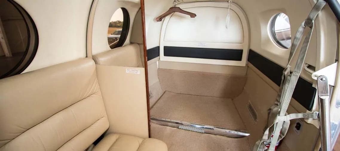 View of the Beechcraft King Air 200 cabin with beige leather seats and a small storage area.