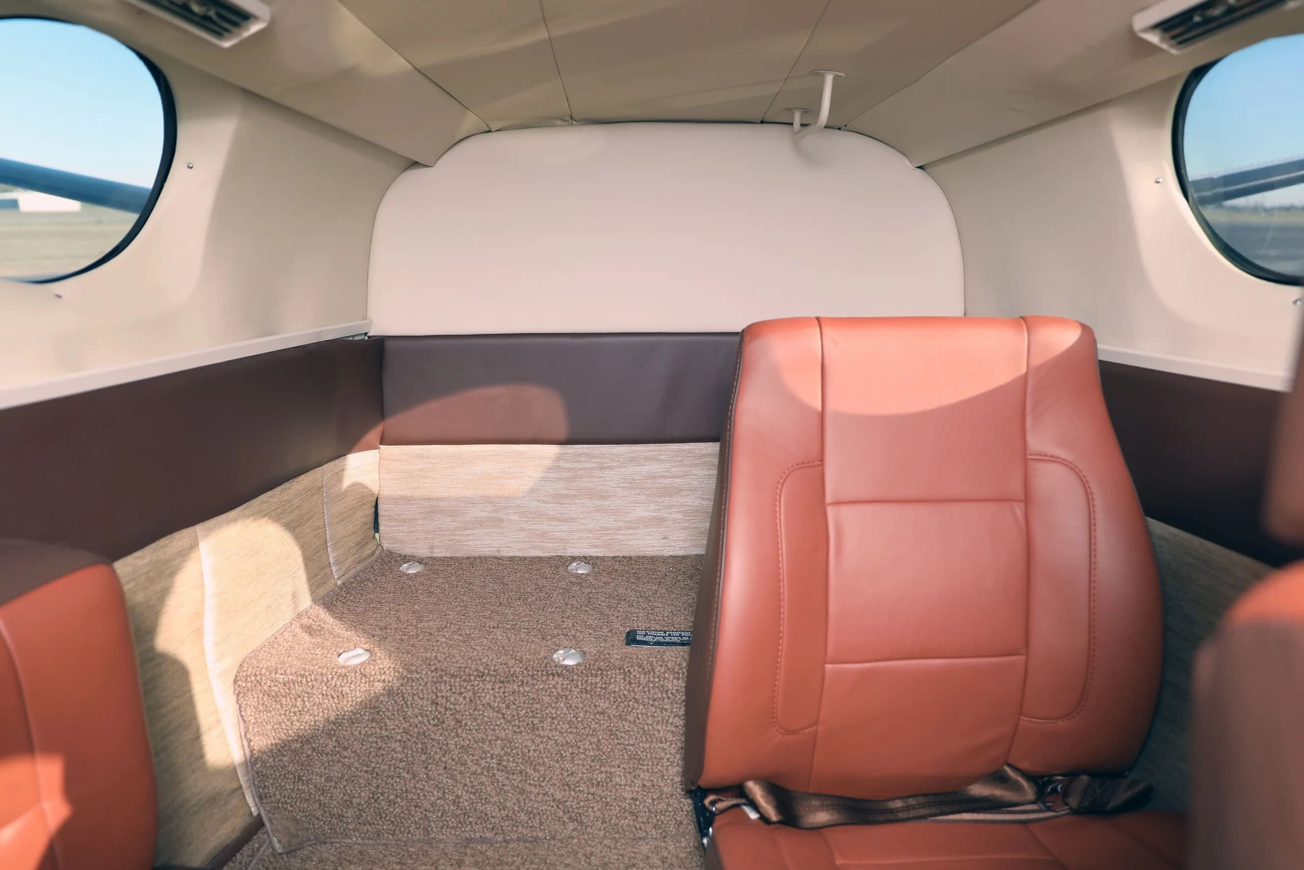 The rear cabin interior of the Cessna 414 Chancellor, featuring a single brown leather seat and carpeted floor.