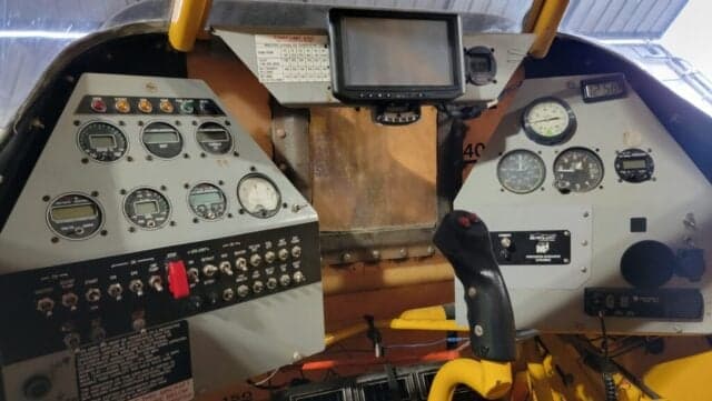 A yellow and black Air Tractor AT-400 sits inside a hangar.