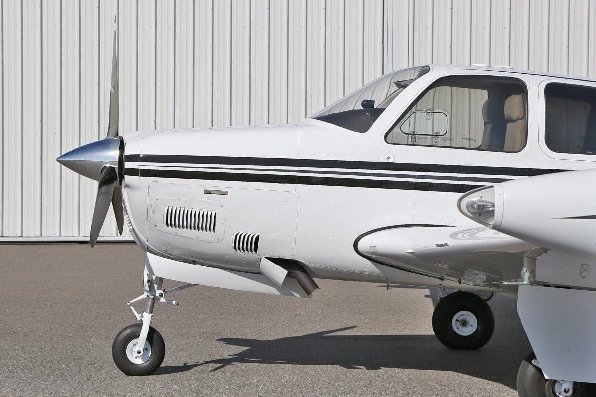Close-up of the front of a Beechcraft Bonanza showing the propeller and landing gear.